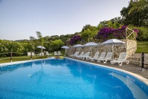 una gran piscina con sillas y sombrillas en Arcaloro Resort, en SantʼAngelo di Brolo
