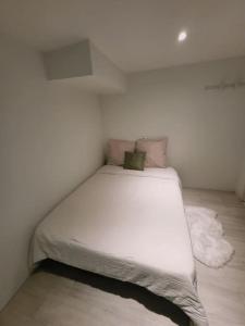 a white bed in a white room with at Appartement charmant américain in Hardricourt