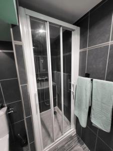 a bathroom with a shower with a glass door at Appartement charmant américain in Hardricourt
