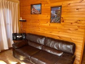 - un canapé en cuir brun dans une chambre dotée de murs en bois dans l'établissement Linda casa en El Manzano con hermosa vista!!!, à Cajon del Maipo
