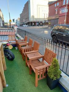 a row of wooden benches sitting next to a fence at Rest and Welcome in Blackpool