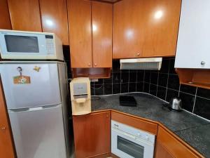 uma cozinha com um frigorífico branco e um micro-ondas em Lovely Waterfront Riverbank Suite with Pool A2 em Kuching