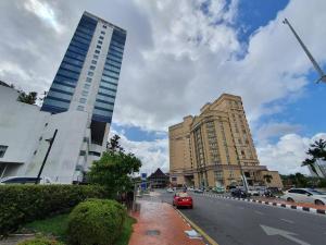 uma rua com dois edifícios altos e um carro vermelho em Lovely Waterfront Riverbank Suite with Pool A2 em Kuching