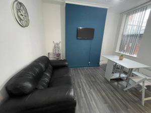 a living room with a black leather couch and a table at Joyous Private Room in City Centre in Liverpool