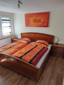 a bedroom with a wooden bed with an orange comforter at Mitten in der Natur, ganz nah bei Dresden. in Bannewitz