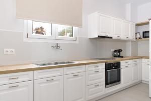 a white kitchen with white cabinets and a sink at KORINA APART HOTEL KAVOS in Kavos