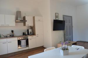 a kitchen with white cabinets and a table and a tv at Gemütliche Ferienwohnung - Prein an der Rax 