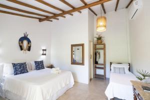 Cette chambre comprend 2 lits dans une chambre dotée de murs blancs et de plafonds en bois. dans l'établissement Pousada Villa Serena, à Caraíva