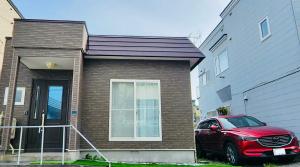 小樽Experience relaxation in Otaru's bungalow的砖屋前的红色汽车