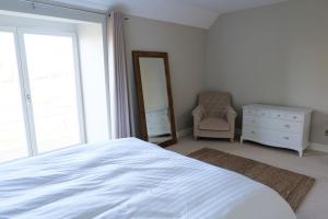 a bedroom with a bed and a dresser and a mirror at Greentrees Estate - The Chestnut Cottage in Balcombe