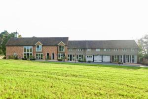 a large brick building with a large grass field at Greentrees Estate - The Chestnut Cottage in Balcombe