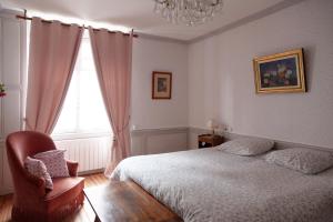 a bedroom with a bed and a chair and a window at les chambres fleuries in Saint-Benoît-du-Sault
