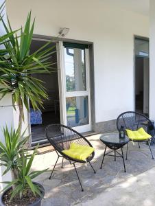 3 sedie con cuscini gialli sedute su un patio di Sleep & Fly Malpensa a Case Nuove