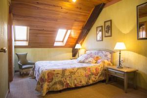 1 dormitorio con 1 cama, 1 silla y 2 ventanas en Casa rural Txikirrin II - Selva de Irati, en Villanueva de Aézcoa