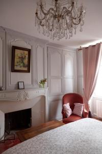1 dormitorio con lámpara de araña, silla y chimenea en les chambres fleuries, en Saint-Benoît-du-Sault