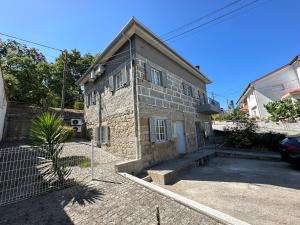 una casa de piedra con un coche aparcado delante de ella en Casa da Poça 2 - Guest House, en Braga