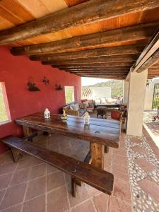 einen Holztisch und eine Bank auf einer Terrasse in der Unterkunft Cortijo Cuscurro in Ríogordo