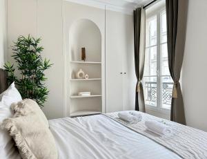 a bedroom with a bed with white sheets and a window at Charming Apartment with Eiffel Tower View in Paris
