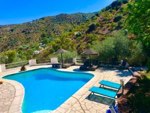 ein Schwimmbad mit einem Berg im Hintergrund in der Unterkunft Cortijo Cuscurro in Ríogordo