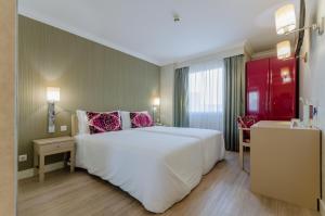 Un dormitorio con una gran cama blanca con almohadas rosas. en Olissippo Marquês de Sá, en Lisboa