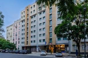 Un gran edificio blanco con coches aparcados delante. en Olissippo Marquês de Sá, en Lisboa