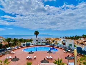 a swimming pool with umbrellas and chairs and the ocean at MARISOL beautiful apartment with oceanview in Adeje
