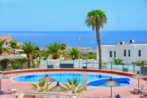 a swimming pool with palm trees and a building at MARISOL beautiful apartment with oceanview in Adeje