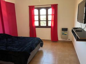 - une chambre avec un lit et une fenêtre avec des rideaux rouges dans l'établissement Dptos Los Pajaritos -El Canario-, à San Salvador de Jujuy
