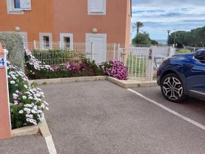a car parked in front of a building with flowers at Villa 6 personnes dans résidence calme, grande terrasse, 5 mn de la plage in Fleury +2 photos