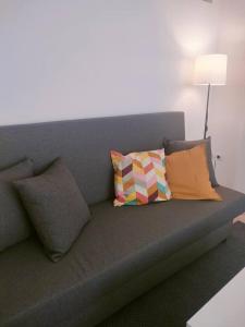 a gray couch with pillows on it in a room at San Centro Wizink IFEMA Metropolitano Airport Apartments in Madrid
