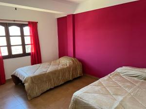 Cette chambre comprend 2 lits et un mur rouge. dans l'établissement Dptos Los Pajaritos -El Canario-, à San Salvador de Jujuy