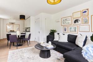 a living room with a black couch and a table at The Ravenscourt Park Escape - Bright 2BDR Flat in London