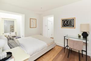 a white bedroom with a bed and a desk at The Ravenscourt Park Escape - Bright 2BDR Flat in London