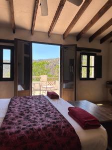 ein Schlafzimmer mit einem großen Bett mit einem großen Fenster in der Unterkunft Cortijo Cuscurro in Ríogordo