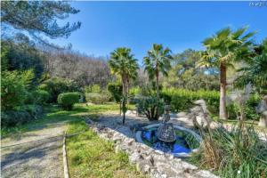 een tuin met een fontein in een tuin met palmbomen bij PROCHE CANNES, SPACIEUX VILLA APPARTEMENT, JARDIN et PISCINE PRIVE in Vallauris