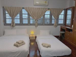 two beds with towels on them in a room with windows at Kong Khong Homestay in Hat Yai