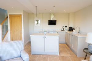 a kitchen with white cabinets and a table and a chair at Greentrees Estate - The Beech Cottage in Haywards Heath