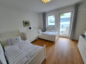 a white bedroom with two beds and a window at East Park Apartments Baumkirchner Str 18 in Munich