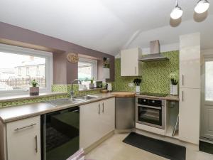 a kitchen with white cabinets and a sink at The Annexe in Lydney