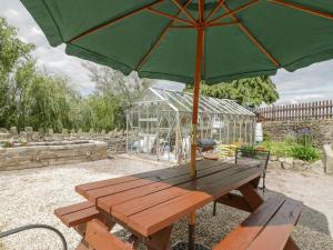 a picnic table with an umbrella and a greenhouse at The Annexe in Lydney
