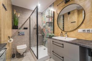 La salle de bains est pourvue de toilettes, d'un lavabo et d'un miroir. dans l'établissement Flatbook Apartamenty - Sztutowo Baltic Sun -B-I-, à Sztutowo