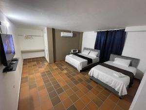 a hotel room with two beds and a flat screen tv at Hotel Valle Central in Valledupar