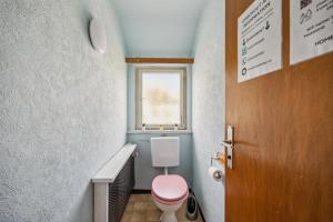 a bathroom with a pink toilet and a window at home2stay worker Apartments Nürtingen-Zizishausen Ap1 in Nürtingen
