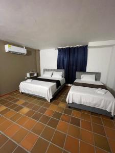 a bedroom with two beds and a tiled floor at Hotel Valle Central in Valledupar