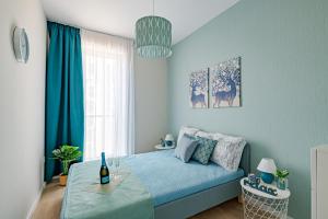 una camera con letto blu e un tavolo con una bottiglia di vino di Waterfront Luxuri a Budapest