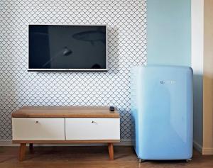 a tv on a wall with a dresser and a dresser with a blue at Blue Apartment Gdańsk in Gdańsk