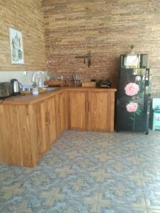 een keuken met houten kasten en een zwarte koelkast bij Gili Rose Private Villa in Gili Trawangan