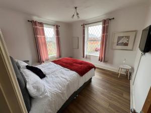 a bedroom with a bed and two windows at Guesthouse Kettering City Centre in Kettering