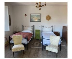 a bedroom with two beds and two chairs at Villa del Borgo in San Benedetto Val di Sambro