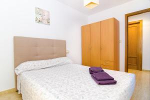 a bedroom with a bed with a purple towel on it at Apartamento de 4 dormitorios muy céntrico en San Juan Pueblo a tan sólo 2,5 km de la playa de San Juan y Muchavista in San Juan de Alicante
